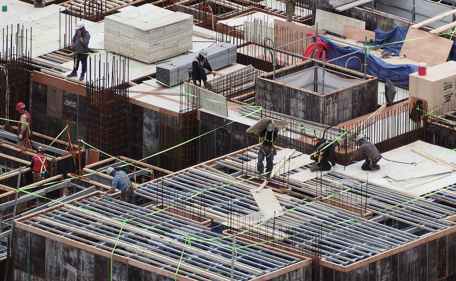 Construction workers installing floor formwork around reinforced concrete columns